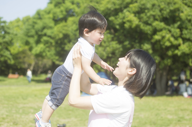 広場で子供を抱き上げる笑顔の保育士